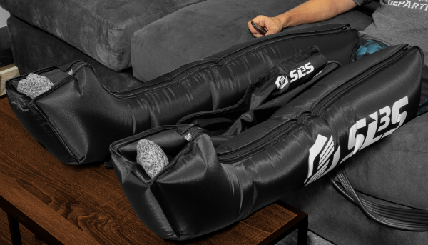 sls3 compression recovery boots being used by an athlete recovering seated in a gray sofa